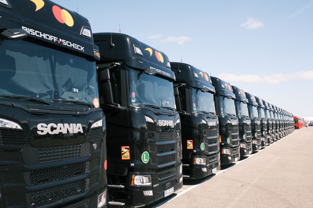 Black Scania trucks lined up outdoors on a sunny day, showcasing transport fleet.